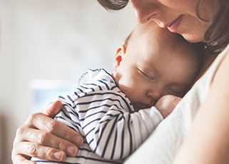 baby sleeping in mother’s arms