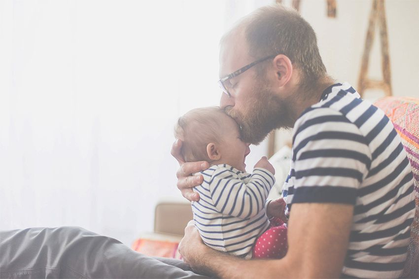 father kissing his newborn baby’s forehead