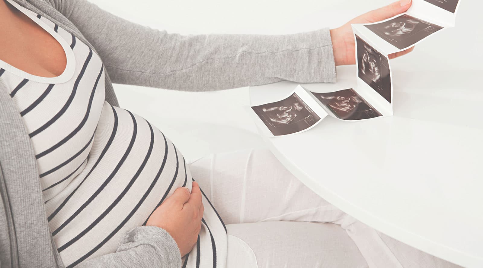 Pregnant mother holding her baby bump while looking at her ultrasound scan
