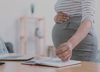 Pregnant mother working at the office and holding her bump