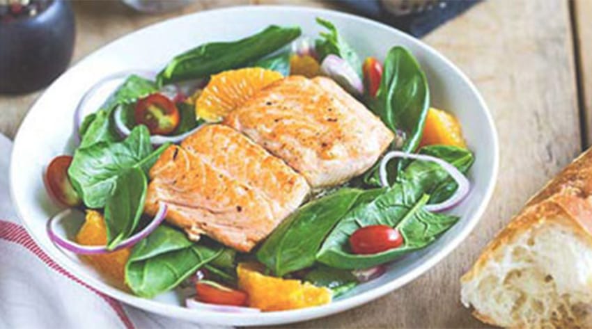 a bowl of salad topped with salmon