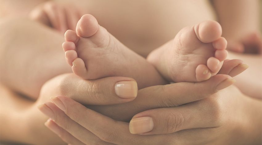 mother holding newborn baby feet