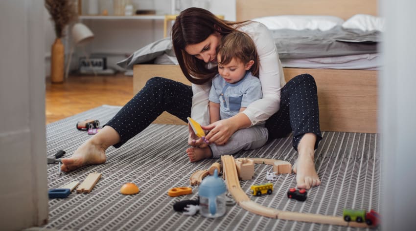 Mother and toddler son playing with toys in the bedroom