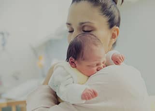 Woman cradling a newborn baby on her shoulder