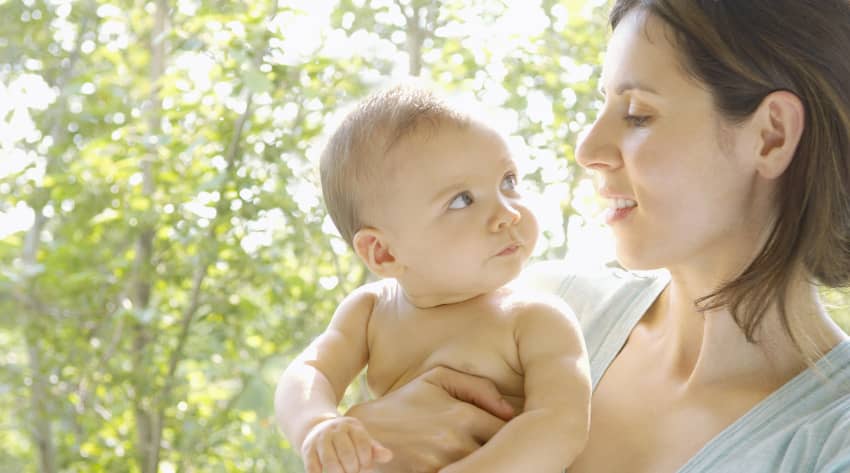 Mother holding and looking at a naked baby in the eyes