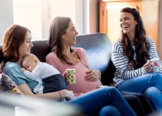 Three mothers chatting and laughing on a sofa
