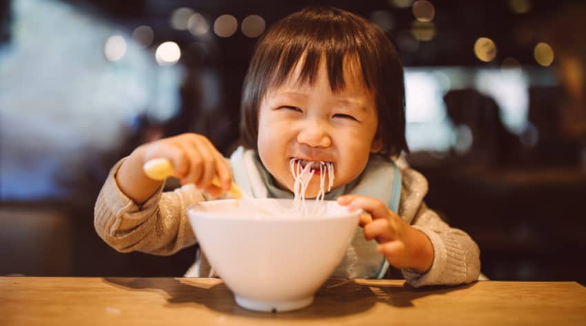 Toddler eating a bowl of noodles