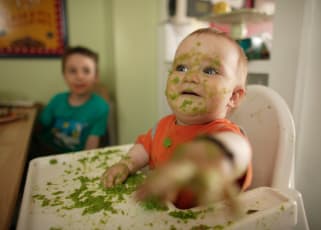 Messy baby eating on a baby chair