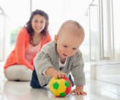 Mum watching baby play with a ball