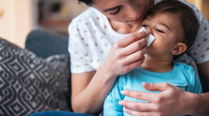 Mum blowing toddler’s runny nose