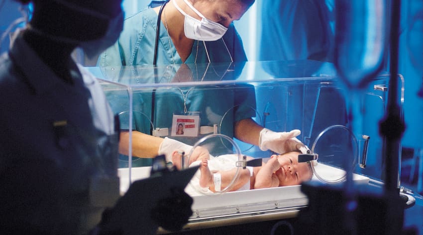A doctor examining a premature baby in neonatal care