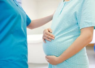 pregnant-mother-holding-baby-bump-speaking-to-nurse