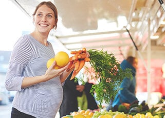 Pregnant mother shopping for organic fruits and vegetables