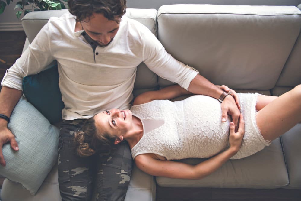 A couple on the sofa together, with the 30 pregnant woman laying her head on her partner's lap