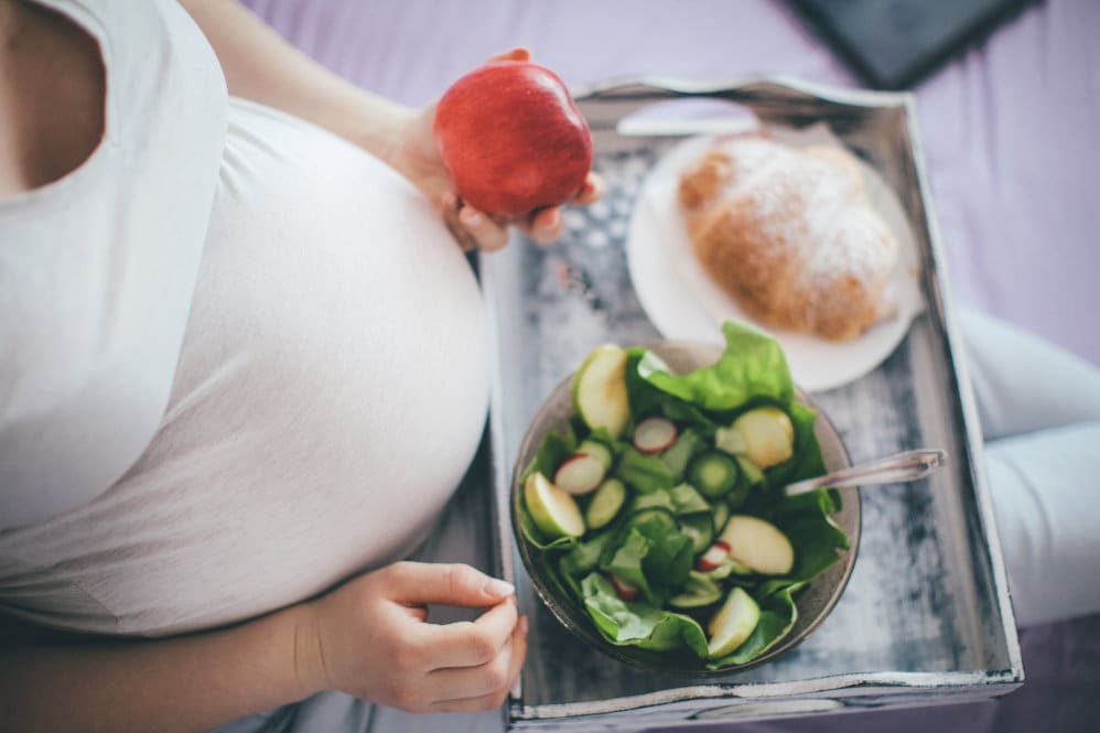 A 34 weeks pregnant woman eating her breakfast in her bed