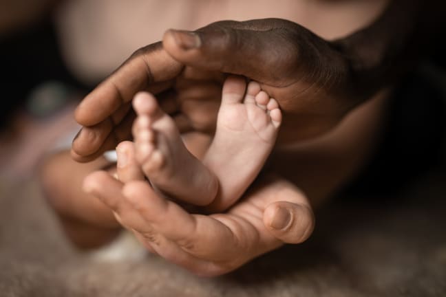 2 newborn feet held by both parents hands.