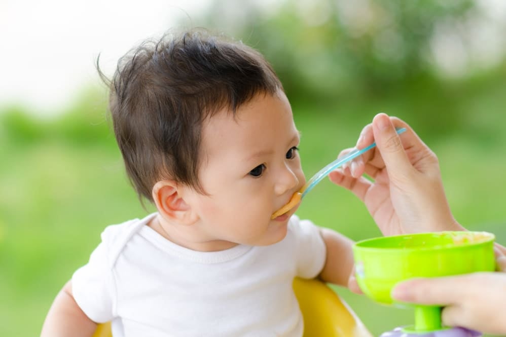 Infant eating from a spoon during mealtime