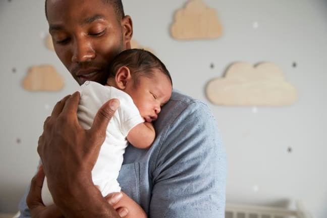 Father holding a baby close against his shoulder