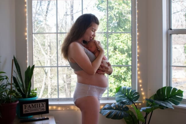Woman holding a baby in front of a bright window