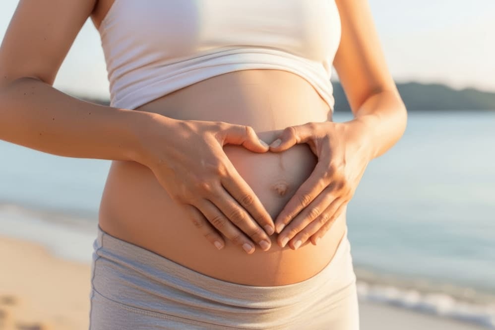 Pregnant woman in third trimester with hands resting on stomach, representing maternal gut microbiome development and the imp