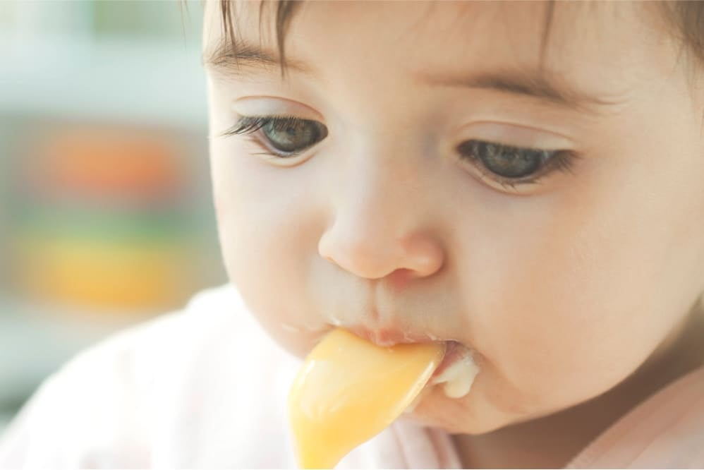 Close-up of a baby being spoon-fed yoghurt