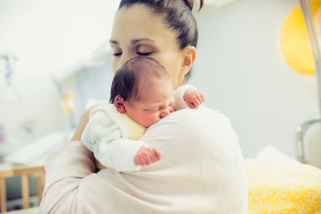 Parent cuddling a newborn baby during early recovery after a C-section