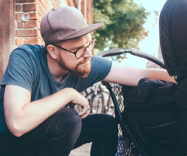 Dad sat down on the street with his hand on a buggy