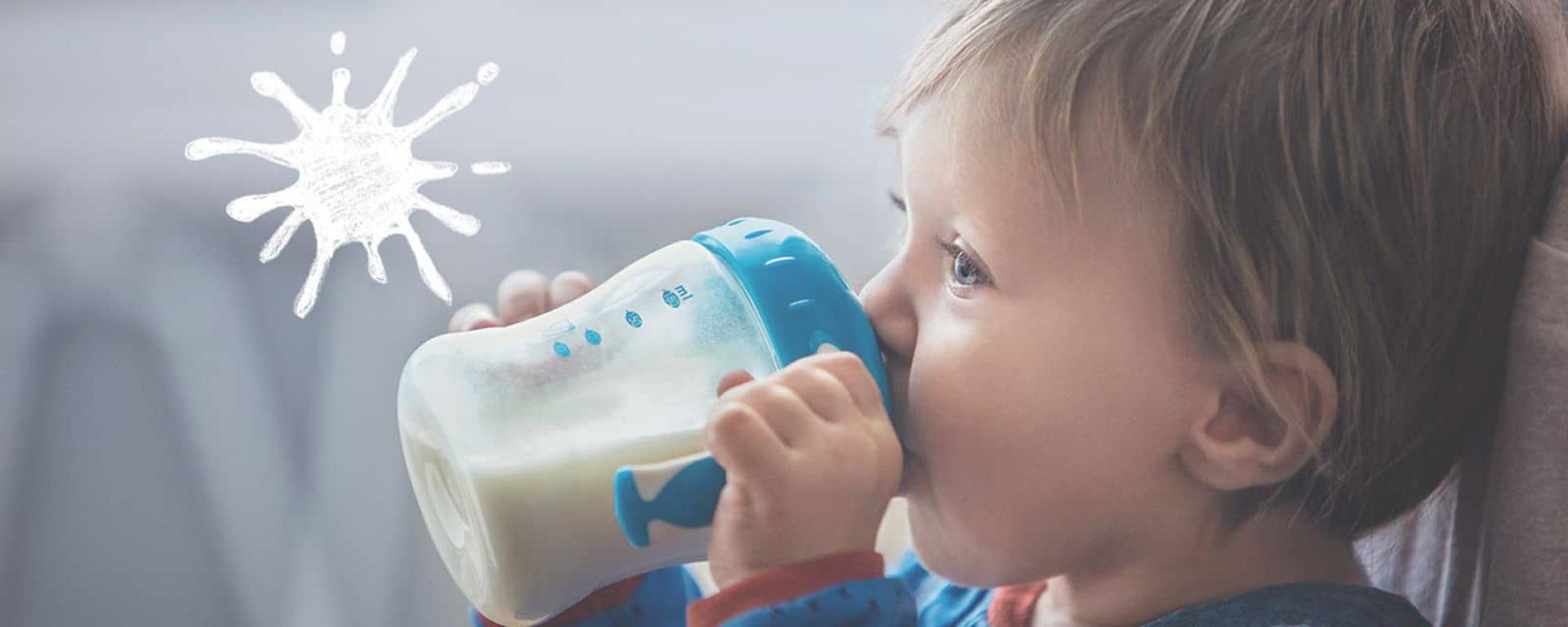 Child drinking follow on milk from a beaker with a blue top